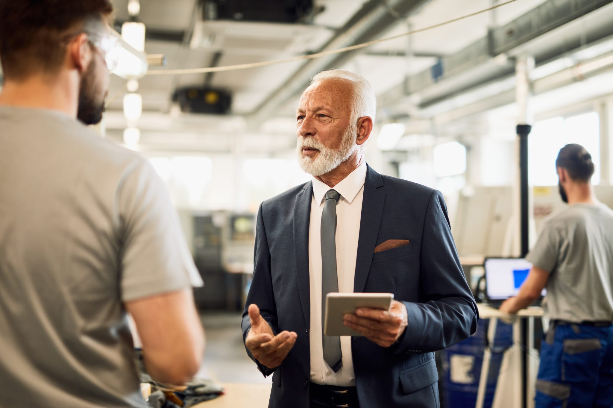 senior company manager talking with a worker in industrial facil